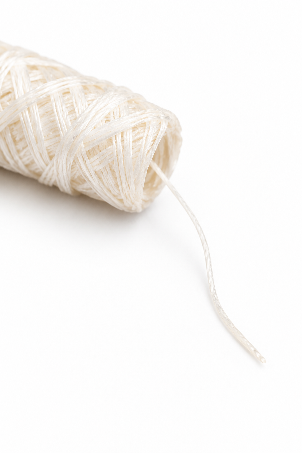 Close-up of ivory silk dental floss refill with an extended thread showing its texture and end.